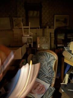 Fauteuil vintage dans un intérieur sombre et encombré. Fauteuil vintage dans une chambre sombre et désordonnée. Un flou de mouvement montre des pages tournées, révélant le portrait d'un bébé souriant.